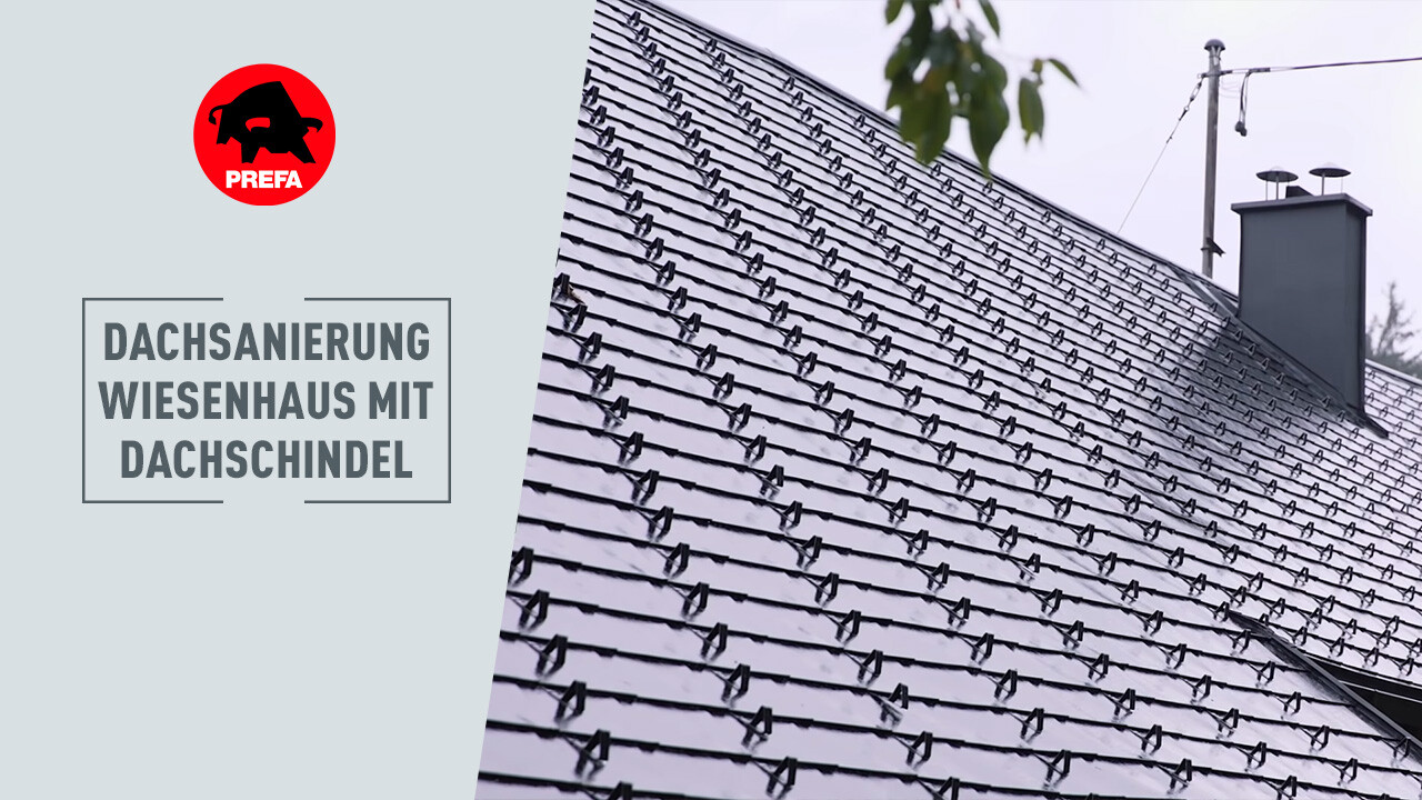 Sanierung eines 400 Jahre alten Bauernhauses Im Vordergrund des Bildes sieht man einen Mann mit weißem T-Shirt, der etwas erklärt. Im Hintergrund ist das Wiesenhaus zu erkennen. Ein 400 Jahre altes Haus, bei dem das Dach mittels PREFA Dachschindeln in der Farbe P.10 renoviert wurde.