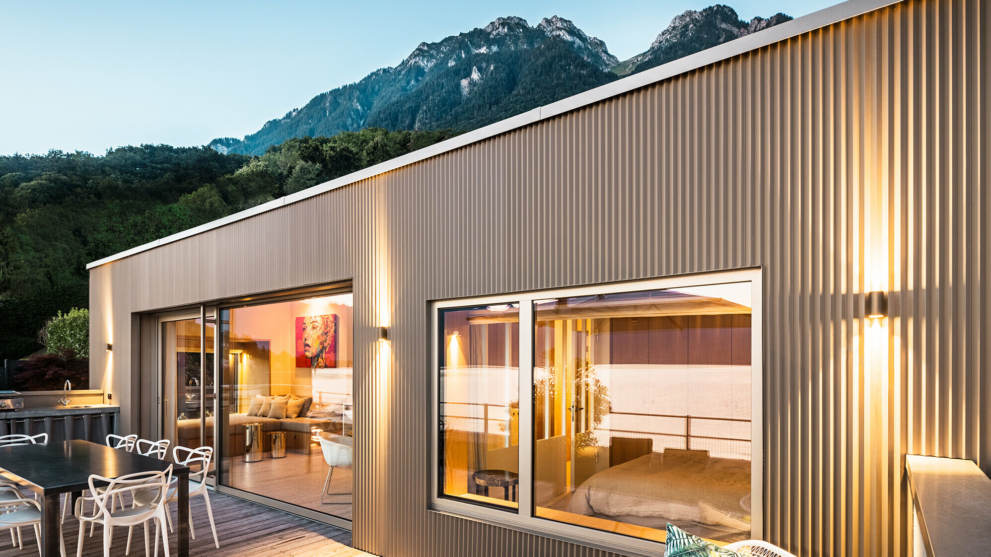 Pogled na terasu i deo unutrašnjosti zgrade uveče.