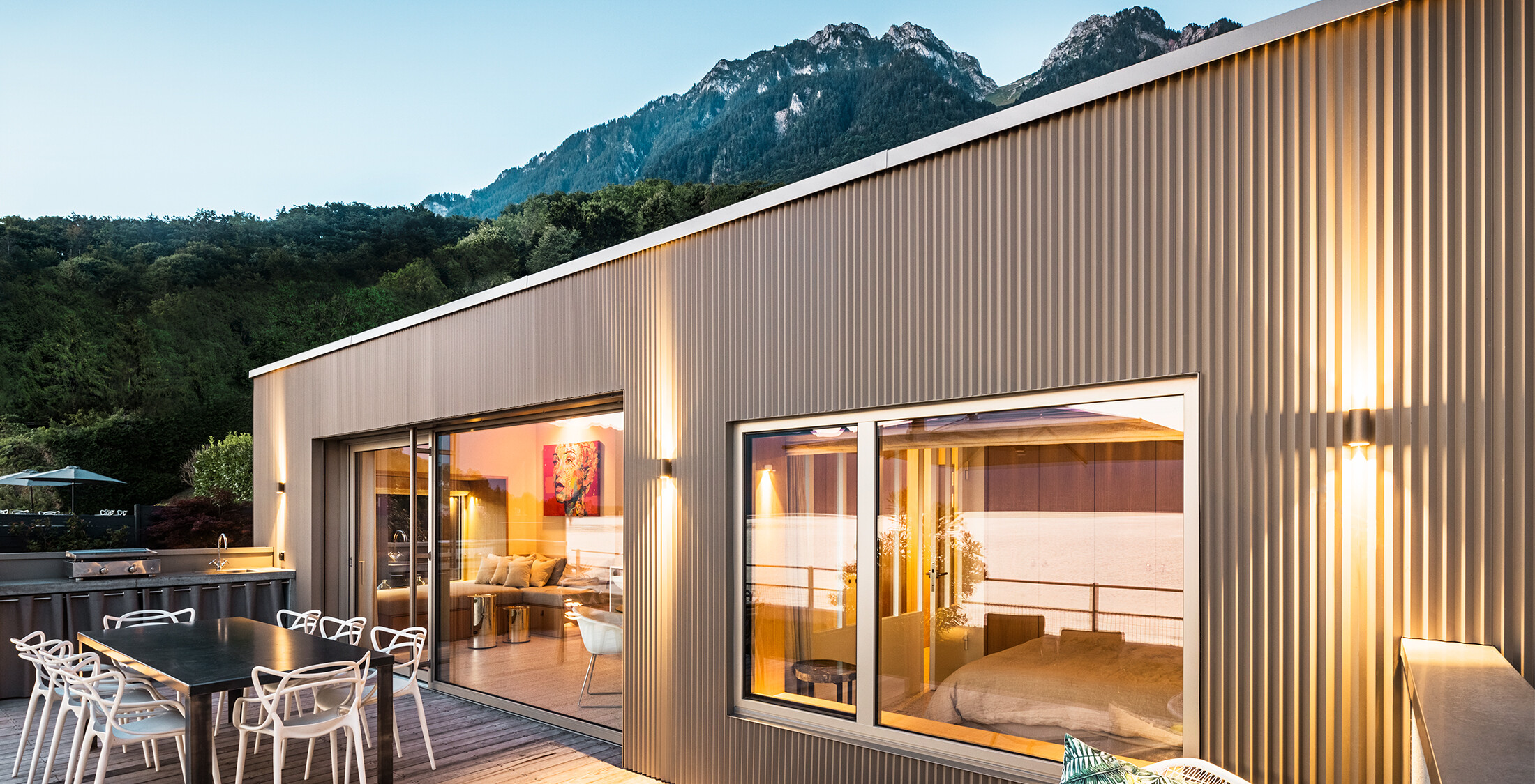 Blick auf die Terrasse und Teil des Gebäudeinneren am Abend.