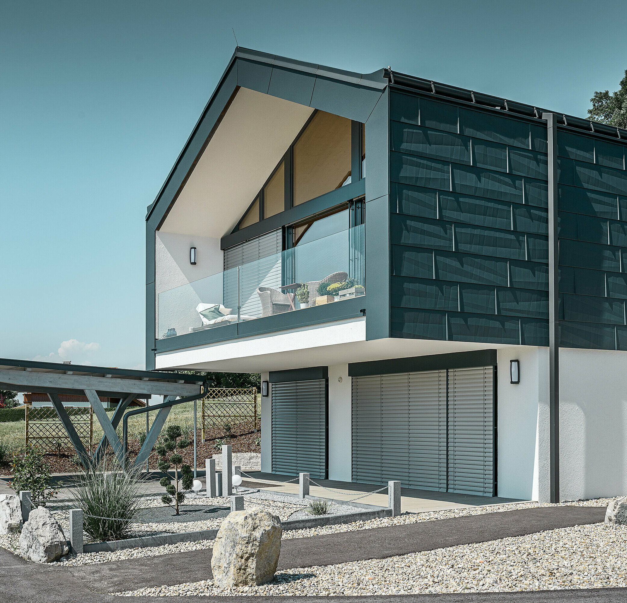 Fassadenverkleidung des Obergeschoßes mit dem PREFA Fassadenpaneel FX.12 in P.10 Anthrazit. Als Ablaufrohr dient das robuste PREFA Quadratrohr.