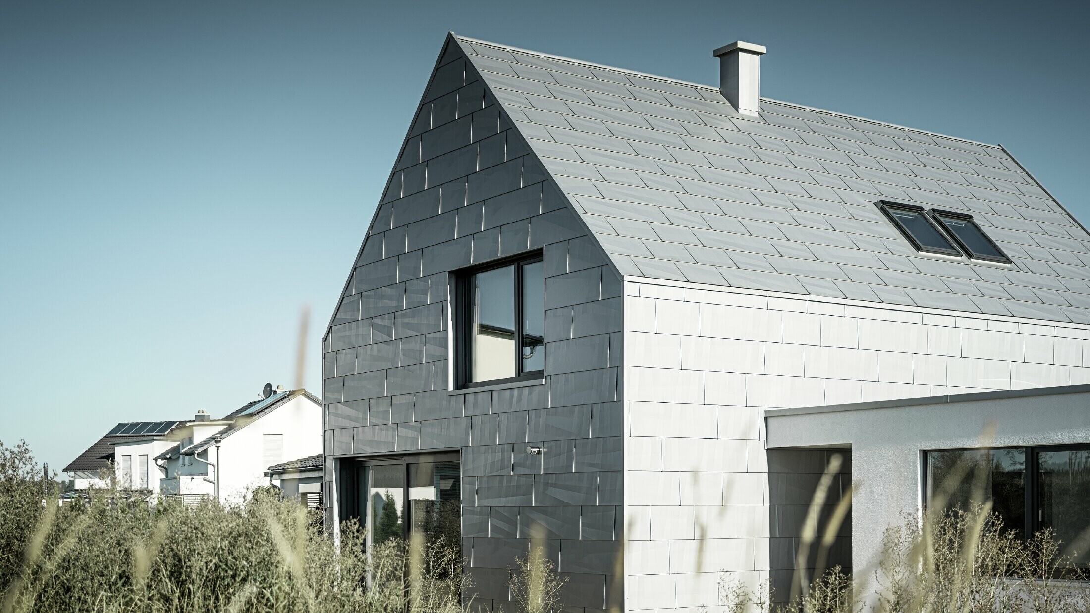 Firmengebäude mit Dach- und Fassadenpaneel FX.12 in der Sonderfarbe Silbermetallic Das Bürogebäude in der Seitenansicht, welches komplett im PREFA Dach- und Fassadenprodukt FX.12 in der Farbe P.10 Silbermetallic gedeckt ist.