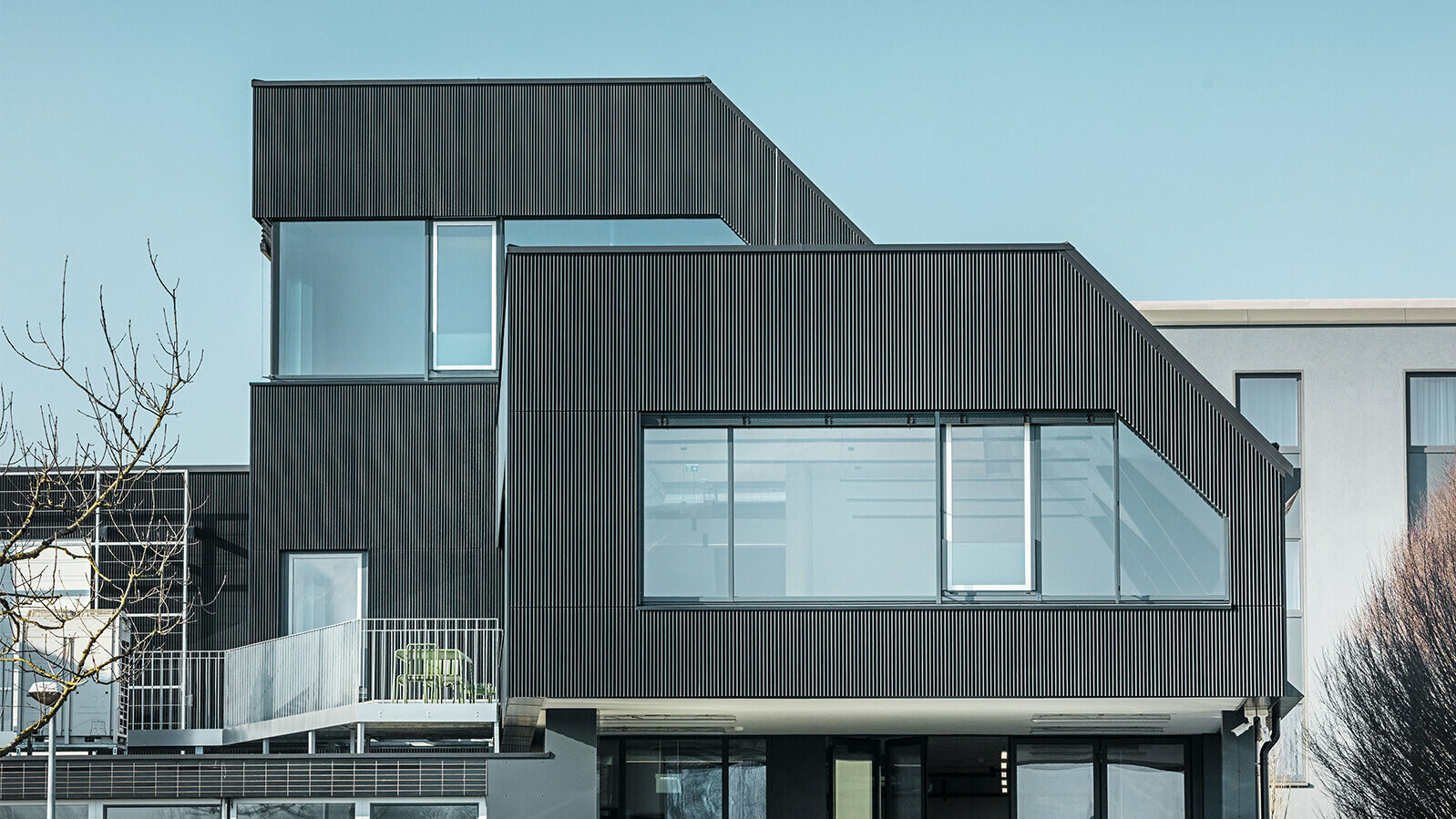 Bočni pogled na zgradu kafića Aman po sunčanom danu. Crni, rebrasti profil je korišćen za zaštitu zgrade.