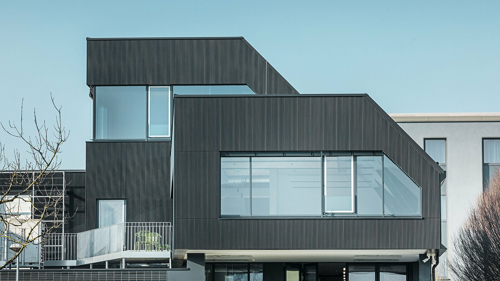 Seitliche Ansicht des Amann-Kaffeegebäudes an einem sonnigen Tag. Zum Schutz des Gebäudes wurde ein geriffeltes Profil in der Farbe Schwarz verwendet.