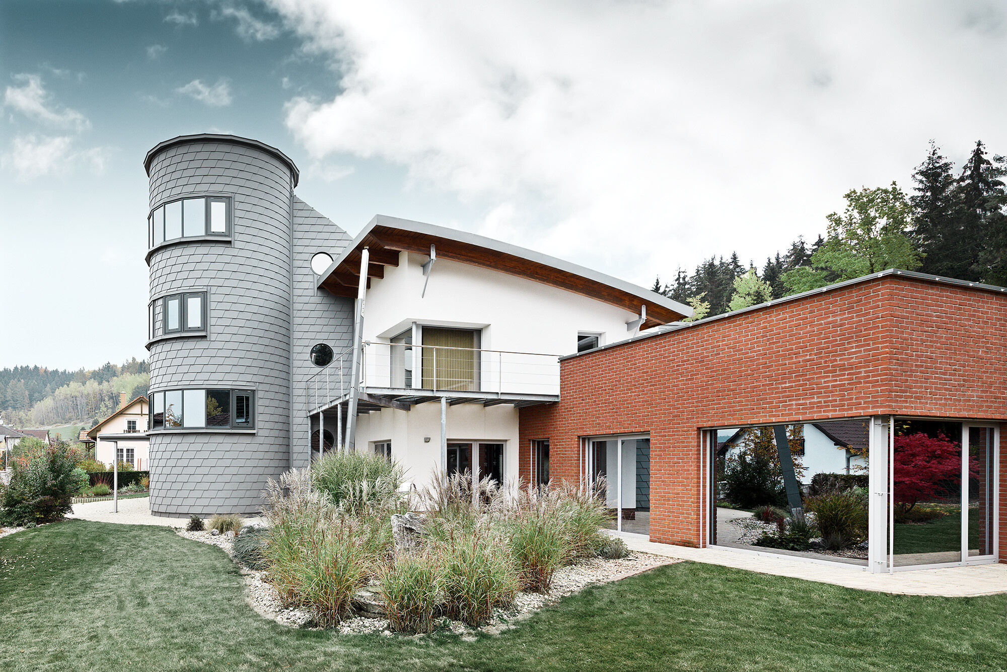 Einfamilienhaus mit Turmzubau, der runde Turm ist mit der PREFA Wandschindel in Patina Grau verkleidet 