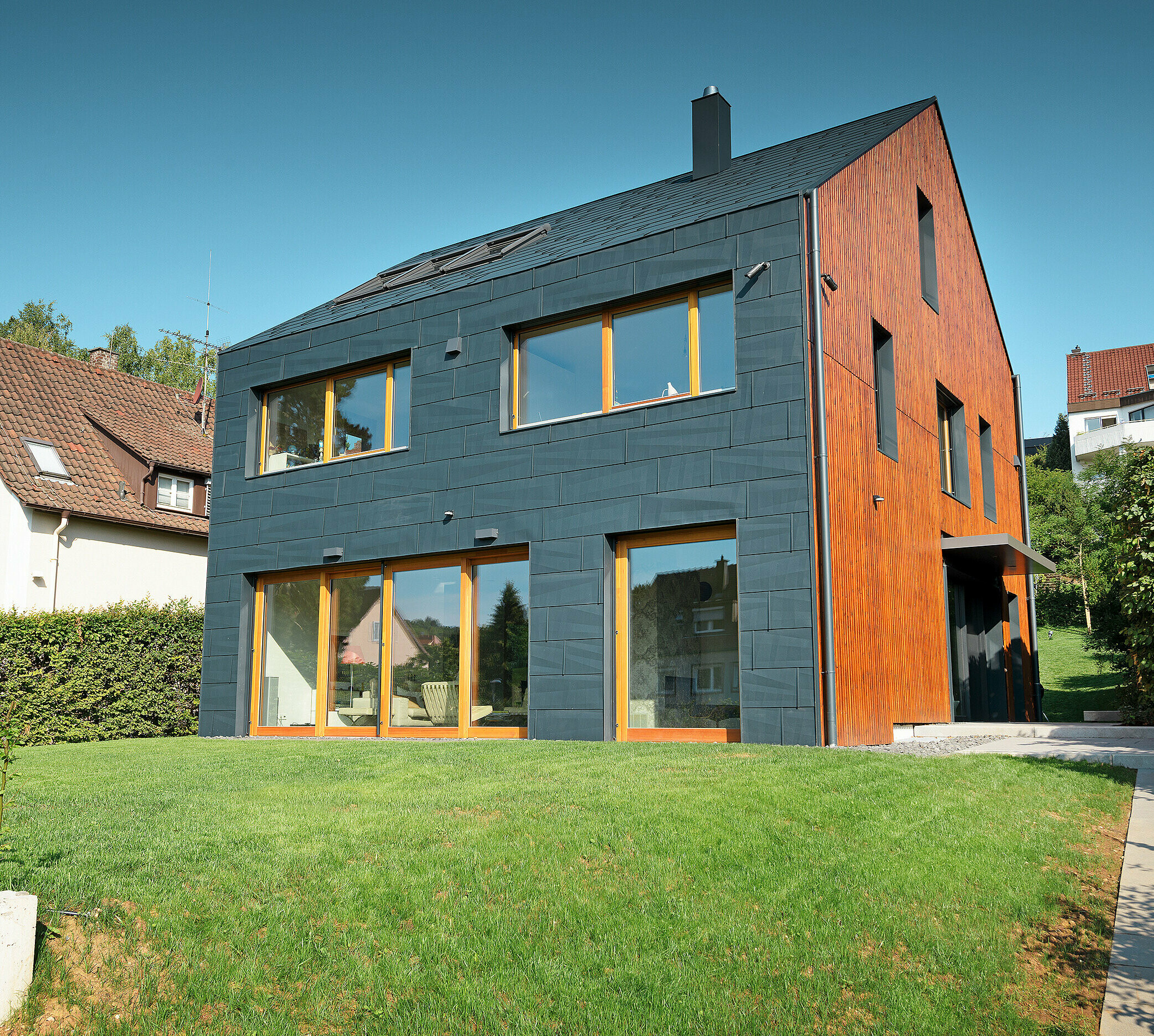 Die PREFA FX.12 Fassade in P.10 Anthrazit zieht sich von der Fassade über das Satteldach, ganz ohne Dachvorsprung.