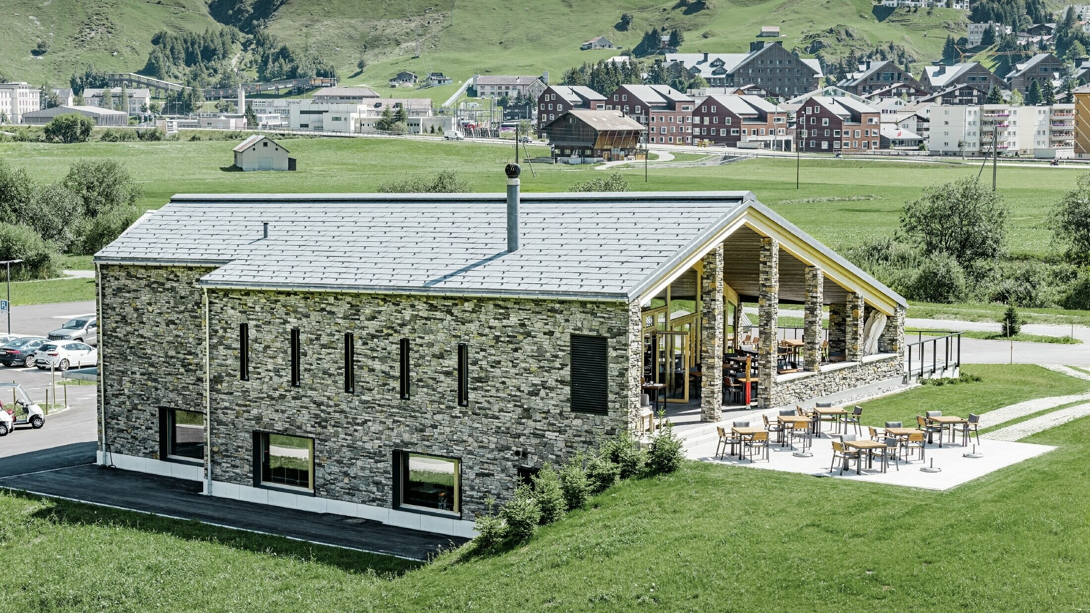 Golfclub-House mit Steinfassade und Dachpaneel FX.12 in Steingrau Modernes Club Haus des Golfplatzes in Andermatt mit Steinfassade und PREFA Dachpaneel FX.12 aus Aluminium in steingrau