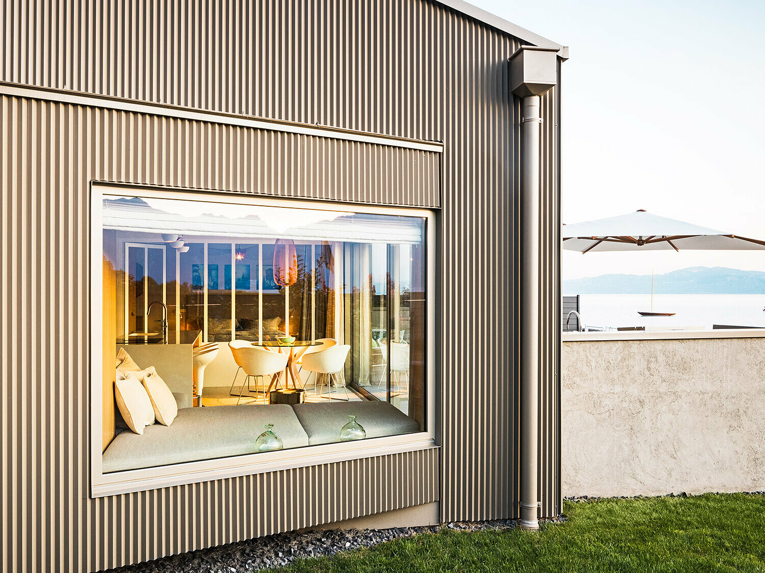 Bočni pogled na zgradu sa zupčastom aluminijumskom fasadom, pri čemu je deo osvetljenog enterijera vidljiv.