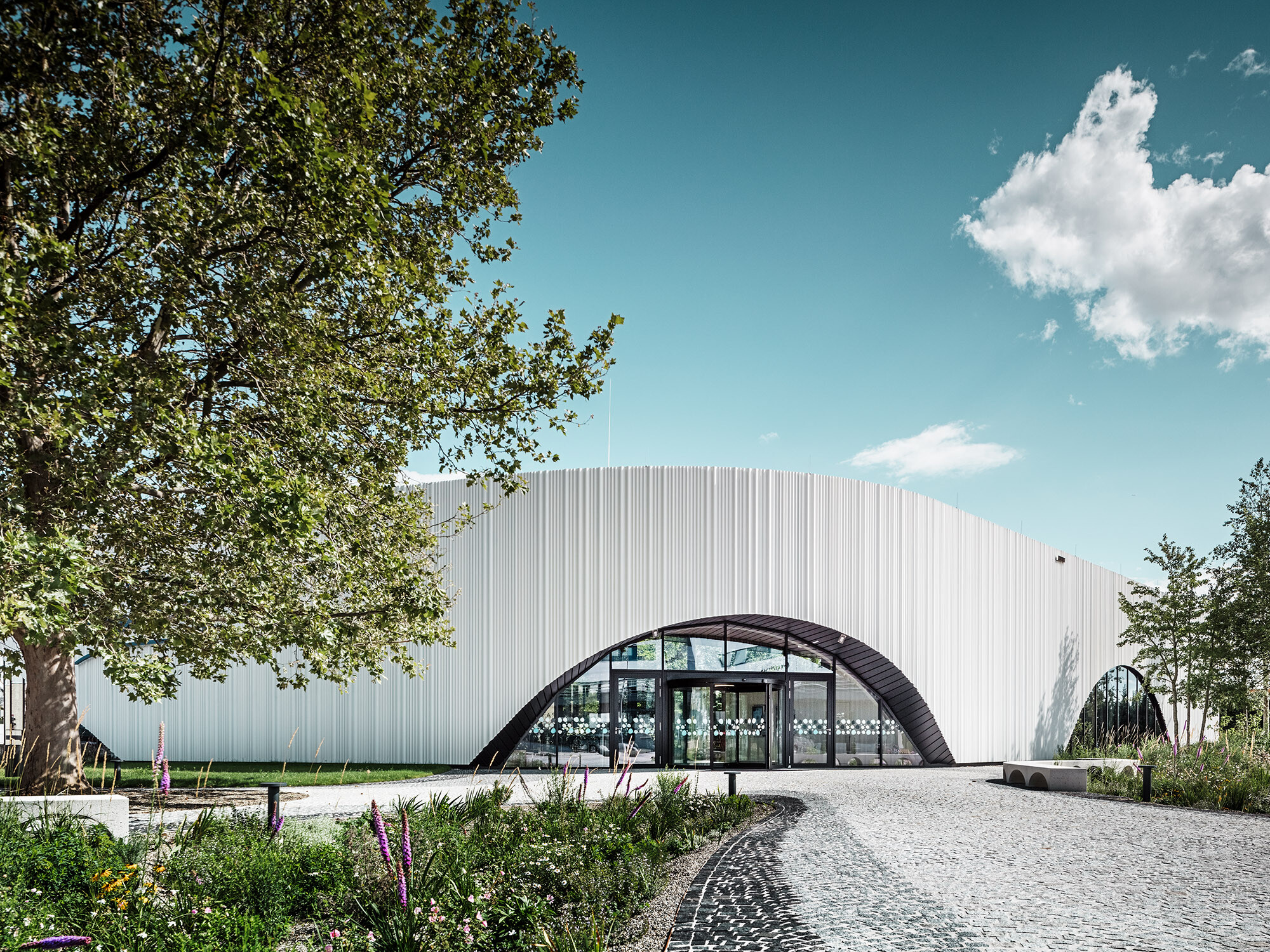 Standardni pogled na restoran Walters sa jednim od njegovih lučnih prozora, usred ozelenjenog okruženja.