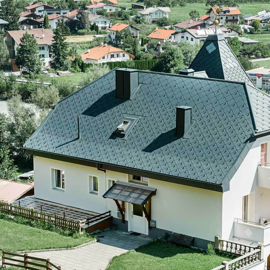 PREFA Dachraute 44 × 44 Anthrazit Referenz Krüppelwalmdach mit einem Turm, eingedeckt mit der Aluminium Dachraute 44 × 44 in Anthrazit.