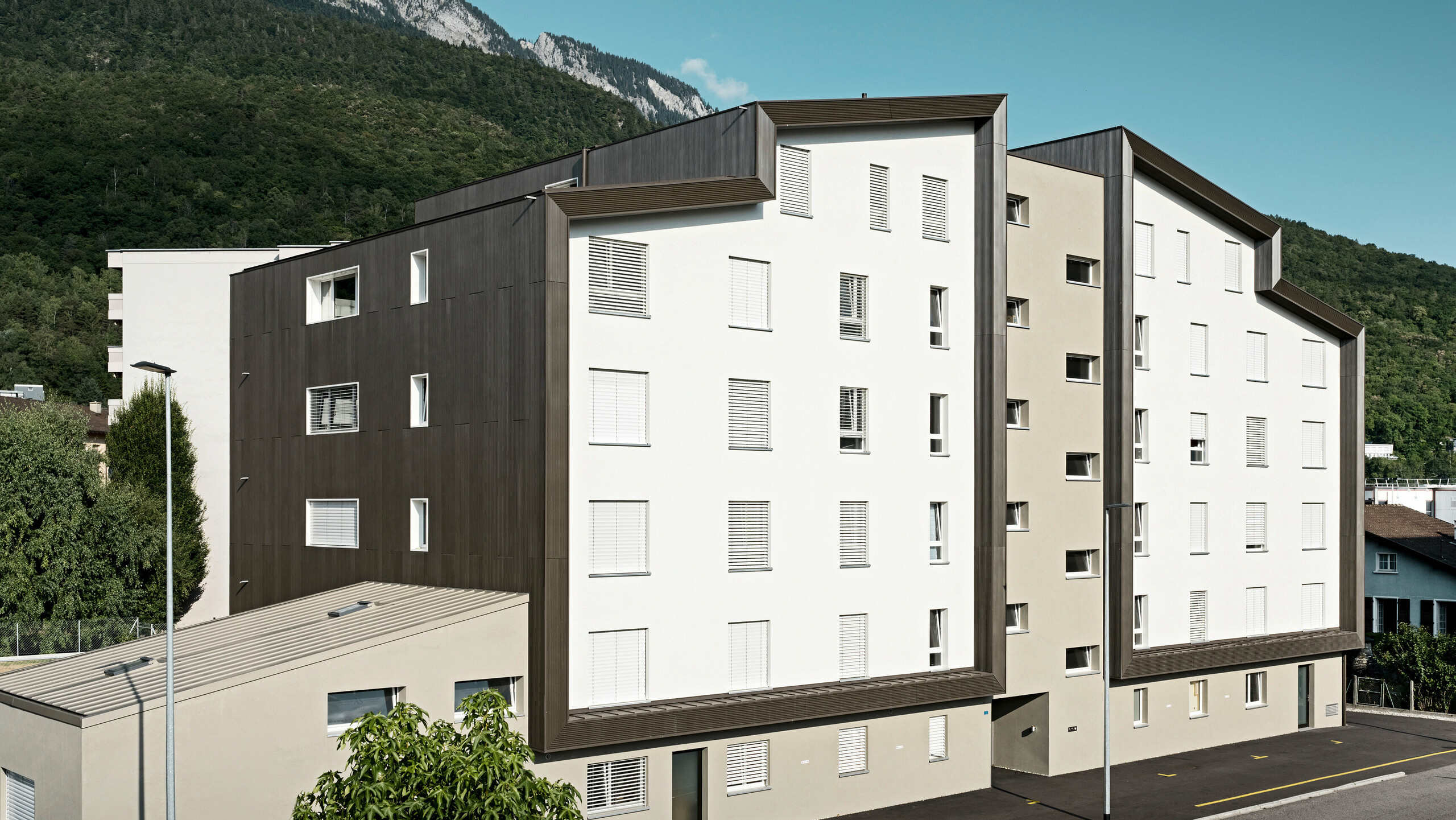 Die Fassade der Wohnhausanlage Les Dailles wurde großflächig mit dem eindrucksvollen PREFA Zackenprofil in Bronze verkleidet. Das Dach des Gebäudes wurde mit PREFALZ in Bronze eingedeckt.