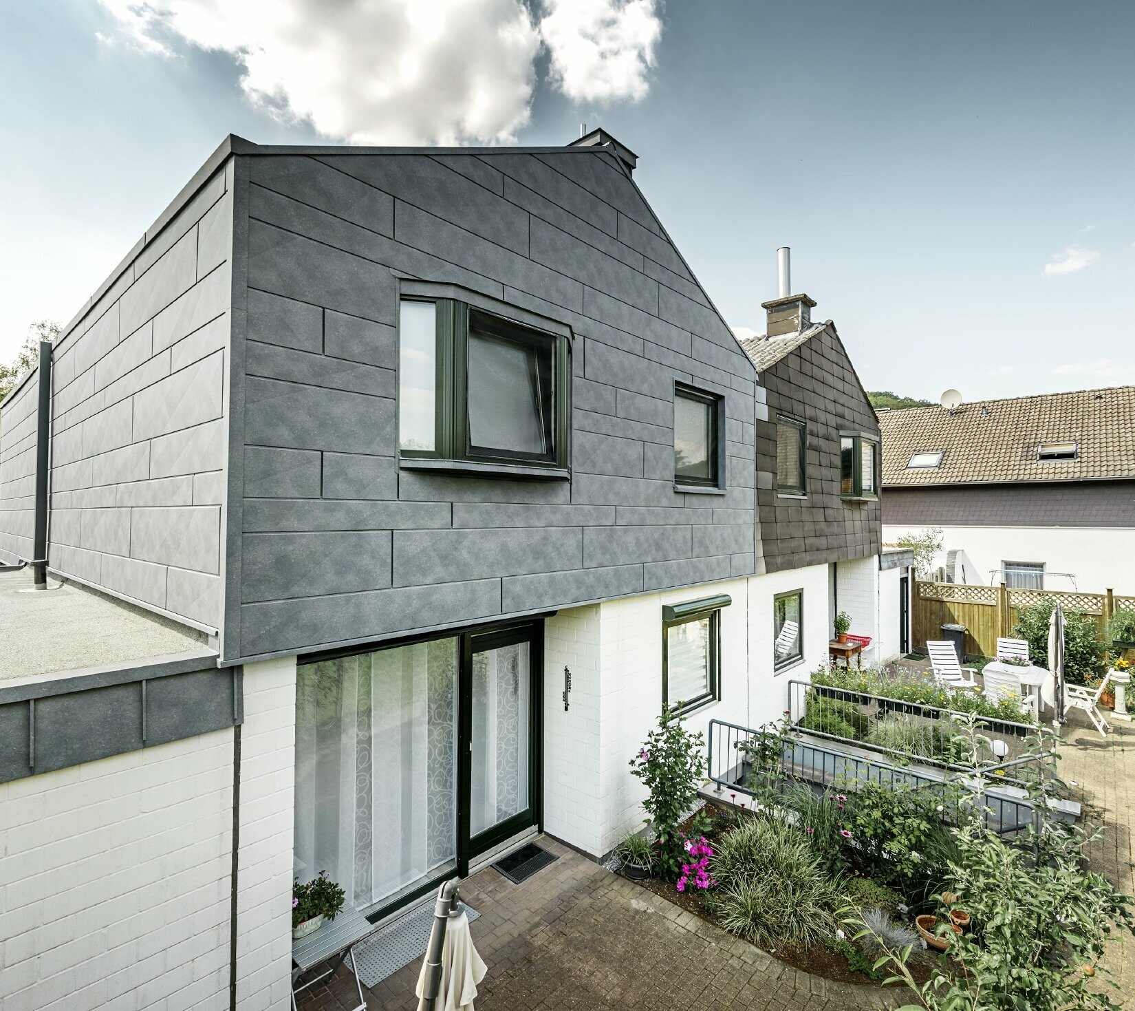 PREFA Haussanierung Fassadengestaltung Siding.X Steingrau Der obere Gebäudeteil der Doppelhaushälfte wurde mit dem PREFA Fassadenelement Siding.X in P.10 Steingrau saniert. Gleich daneben zum Vergleich die Haushälfte vor der Sanierung.