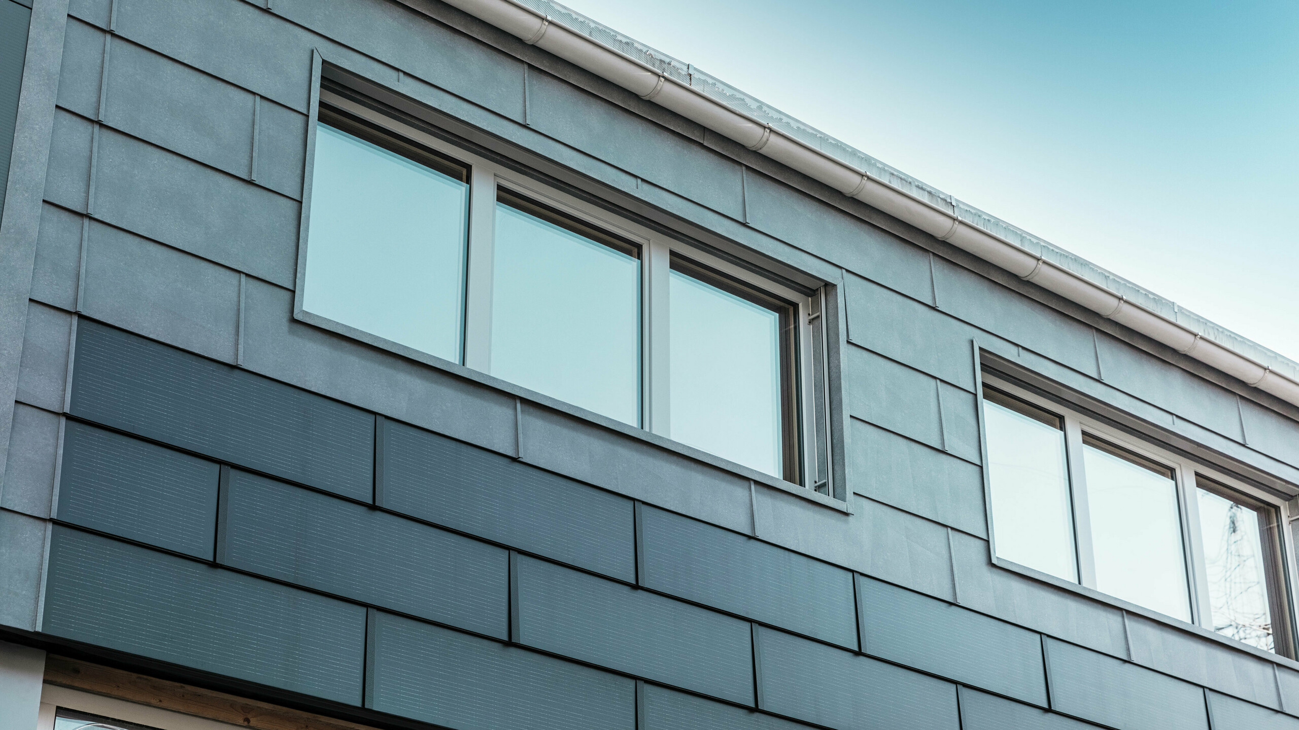 Die Fassadenfläche des Firmengebäudes wurde mit den innovativen Solardachplatten, kombiniert mit den FX.12 Fassadenpaneelen von PREFA, bekleidet.