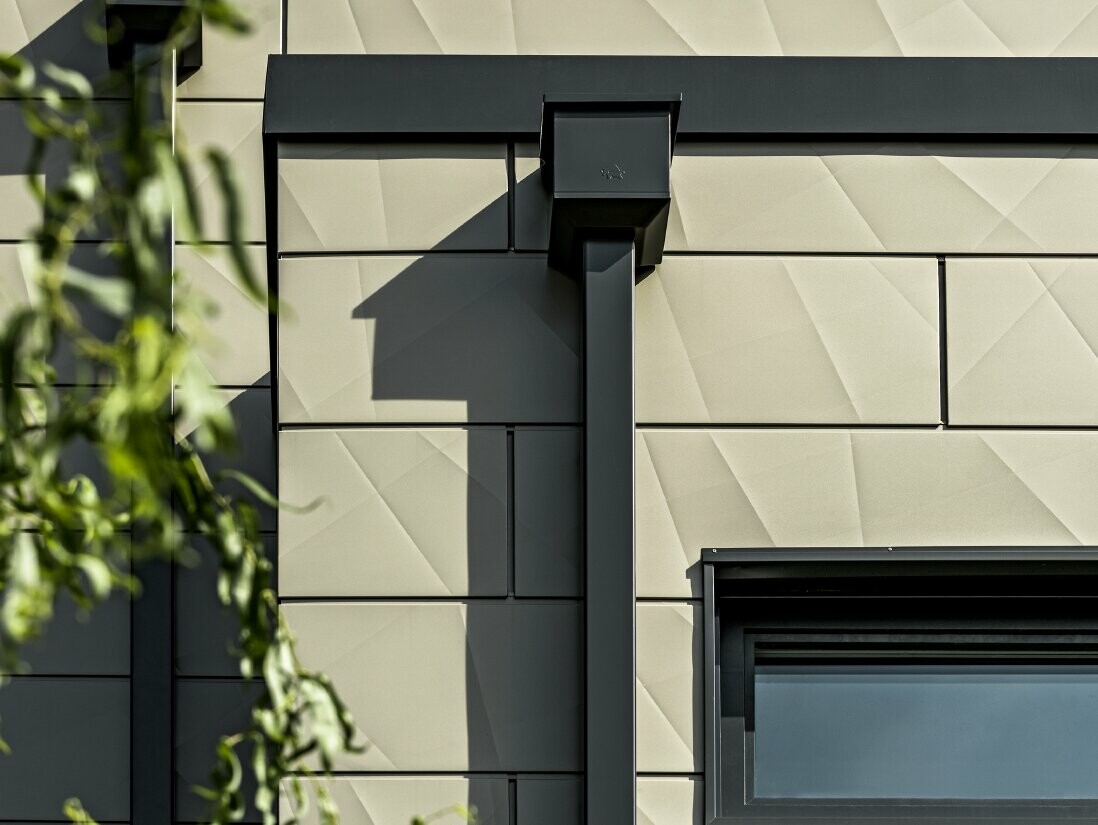 Modernes Einfamilienhaus mit PREFA Siding.X in Bronze und PREFA Quadratrohr in Anthrazit Modernes Einfamilienhaus mit Flachdach und schmalen Fenstern. Die Fassade ist mit der PREFA Siding.X Fassade im faltigen Look in der Farbe Bronze verkleidet. Die Anschlüsse wurden in Anthrazit gemacht. Zur Dachentwässerung dient das PREFA Quadratrohr mit dem dazu passenden Wasserfangkasten in Anthrazit.