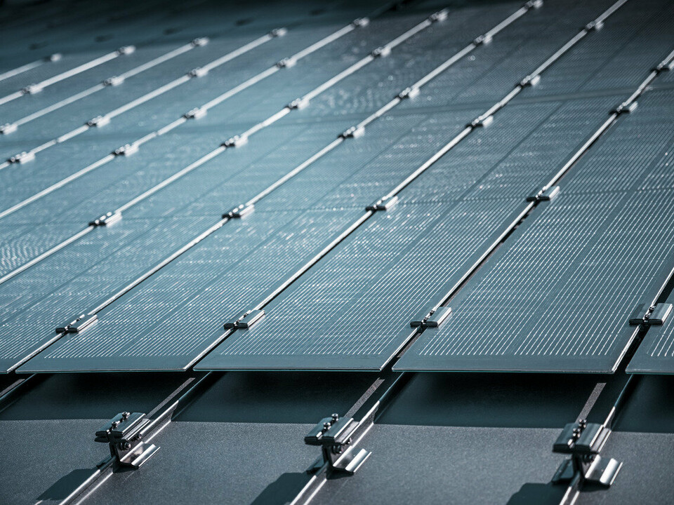 Detailaufnahme von Solarzellen, die auf einem PREFALZ Dach montiert sind, mit sichtbaren Montageschienen und Verbindungsmechanismen, die die Photovoltaikmodule stabilisieren.
