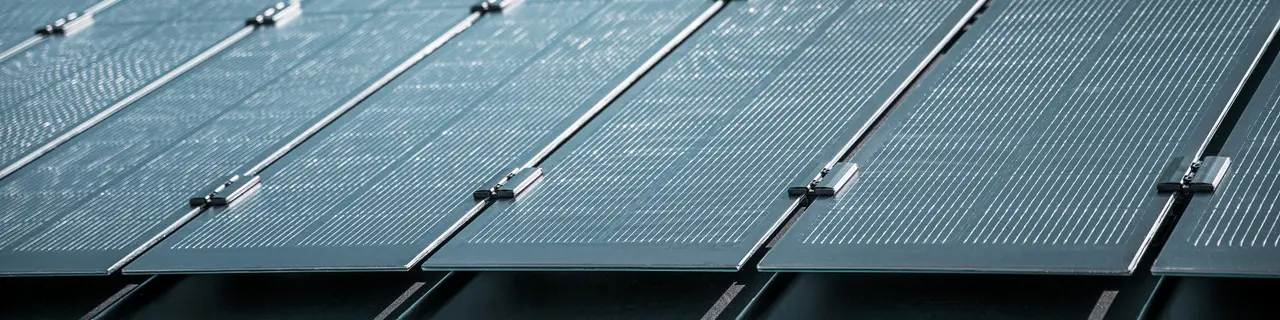 Montageansicht mehrerer PREFALZ Solarmodule auf einem bestehenden PREFALZ Dach in Meschede, Deutschland. Die rahmenlosen Glas/Glas-PV-Module sind in präzisen Reihen angeordnet und mit robusten Halterungen fixiert, was eine flächenbündige, elegante Optik erzeugt. Die hochwertige Befestigungstechnik sorgt für Stabilität und Langlebigkeit, während die innovative TOPCon-Zellentechnologie maximale Energieeffizienz garantiert. Das Bild vermittelt modernste Photovoltaik-Lösung, die Design, Funktionalität und Nachhaltigkeit perfekt vereint.