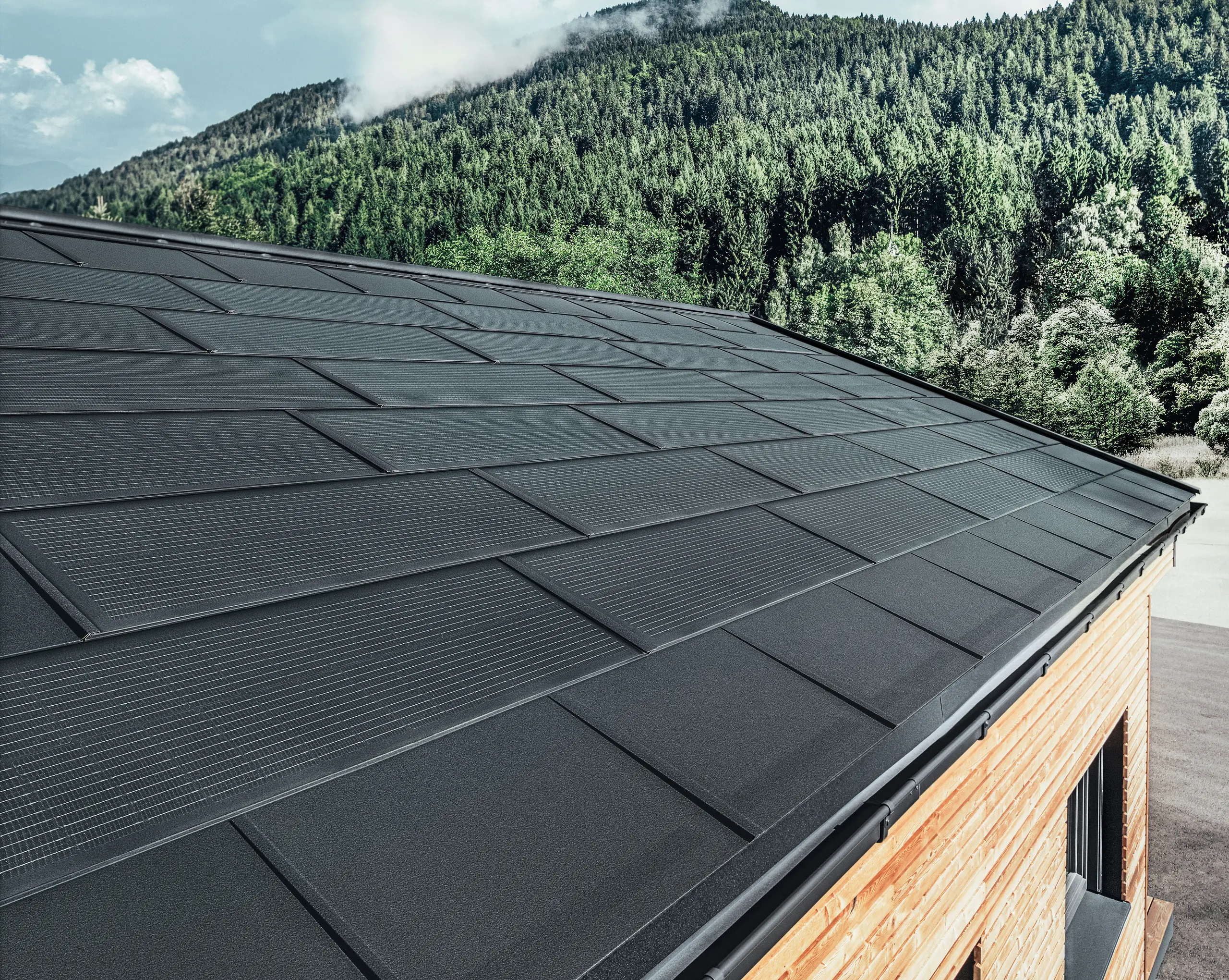 PREFA solarna krovna ploča u velikom formatu, u kombinaciji sa krovnom pločom R.16 u crnoj boji, četvrtastim olukom i fasadom od ariša.