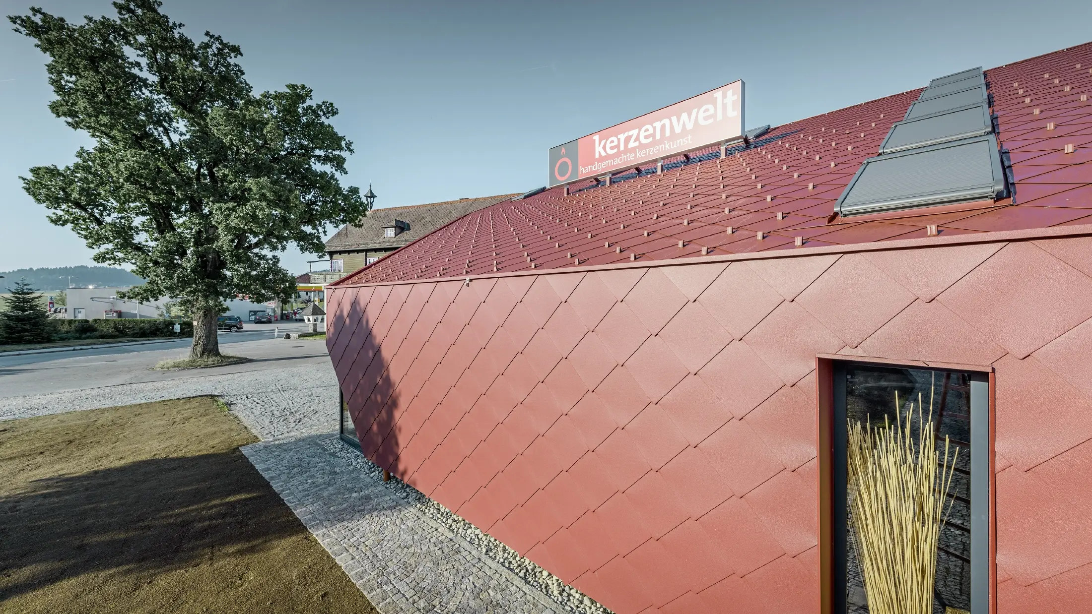 Prodavnica sveća 'Kerzenwelt' u Šleglu je kompletno prekrivena novim PREFA rombom. Krovni pokrivač i fasadna obloga izvedeni su sa rombom 44 × 44 u oksid-crvenoj boji.