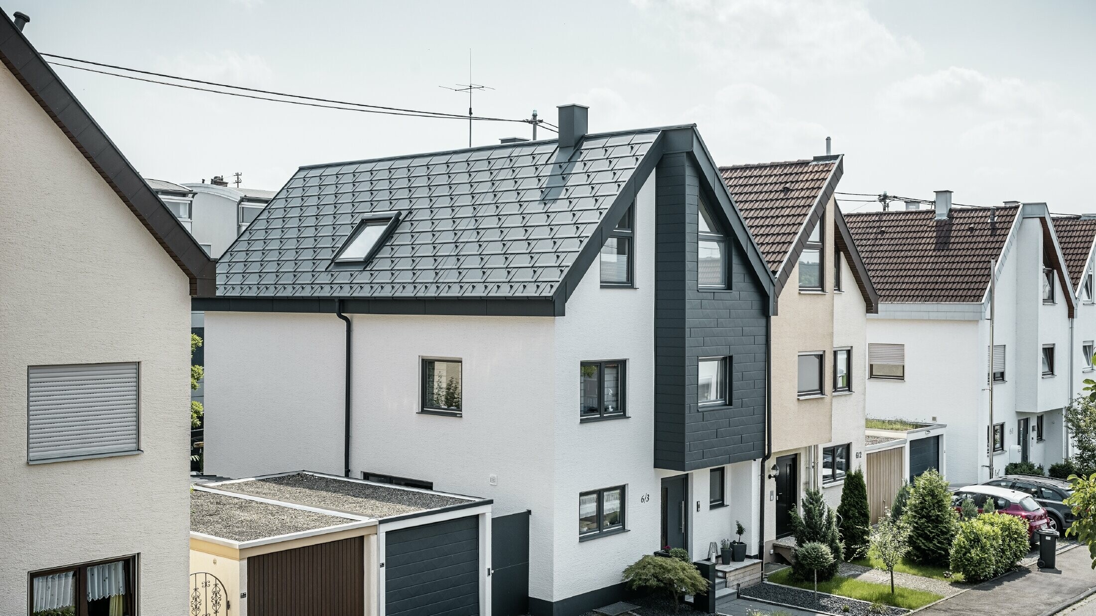 Doppelhaushälfte mit Dachplatte R.16, Kastenrinne und Siding.X in Anthrazit Eine Doppelhaushälfte wurde bereits saniert, mit frischer weißer Putzfassade, kombiniert mit einer PREFA Siding.X Fassade in Anthrazit. Das Dach wurde mit der PREFA Dachplatte R.16 eingedeckt. Die Dachentwässerung erfolgt über die eckige Kastenrinne inklusive PREFA Ablaufrohr.