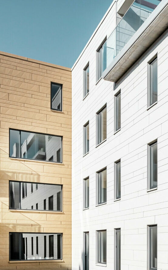 Moderne Gebäude mit PREFA Siding.X Fassade in zwei Farben, die das innovative Fassadenmaterial und die moderne Architektur betonen.